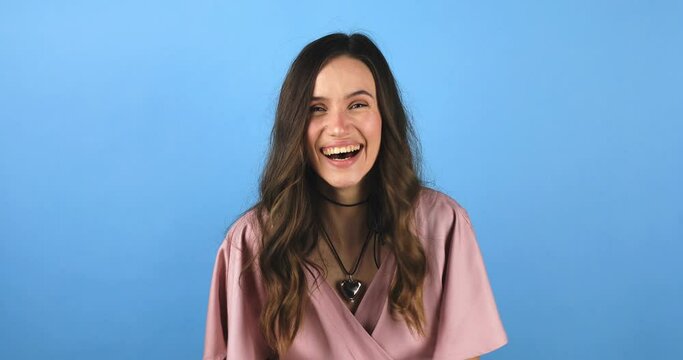 Amazed excited woman hairstyle in pink dress open mouth in surprise looking at camera with big eyes, shocked isolated on blue background. Oh my god wow, yes gesture, win dance.