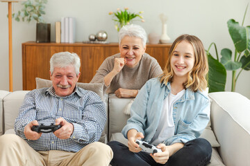 Happy family at home. Old senior man grandfather woman grandmother girl granddaughter playing video...