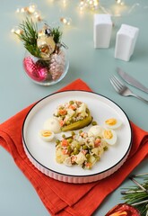 Traditional Olivier salad or Russian salad of boiled vegetables, canned peas and chicken in a modern serving on a white plate on a plain background in New Years style.