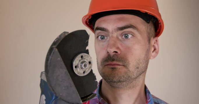 Surprised man with part of broken saw disk stuck in protective goggles against renovated room wall. Handyman shows importance of personal safety equipment