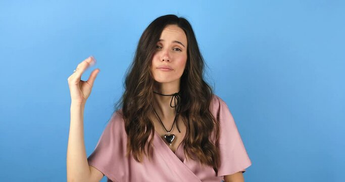 Brunette indignant woman showing blah blah blah gesture with hands isolated on studio blue background. Empty promises, blah concept. Lier, not interested. Annoyed girl making bla bla bla hand gesture.