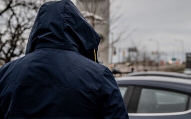 A car thief is breaking into a car in broad daylight in Toronto, Ontario, Canada.