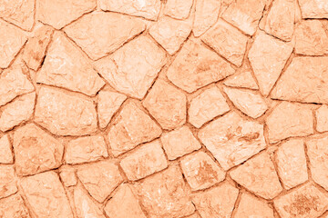 Old grunge stone wall background, texture. Demonstrating color of the year 2024 Peach Fuzz