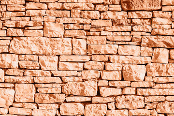 Old grunge stone masonry background, texture. Demonstrating color of the year 2024 Peach Fuzz
