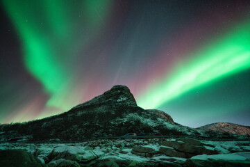 Northern lights and snowy mountains at night in Lofoten, Norway. Aurora borealis above the snow...