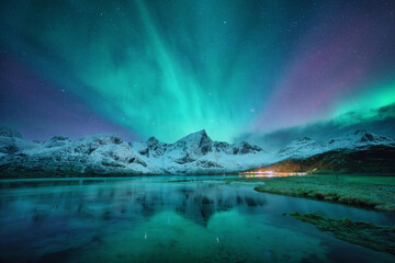 Northern lights over the snowy mountains, frozen sea, reflection in water at winter night in Lofoten, Norway. Aurora borealis and snowy rocks. Landscape with polar lights, starry sky and fjord. Nature - Powered by Adobe