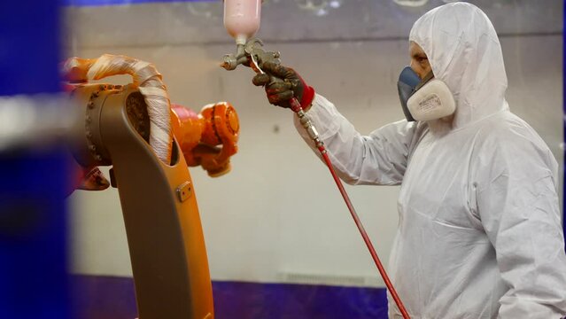 Worker using a paint spray gun in a factory.