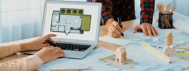 Professional architect represented ECO house displayed on laptop to project manager on messy table...