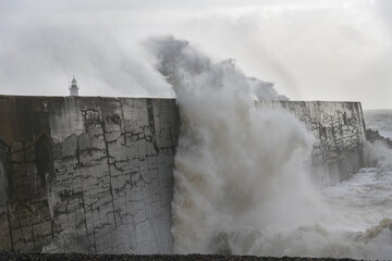 Fototapeta premium Stormy weather in Newhaven, East Sussex, England in autumn. View of the jetty and the lighthouse.