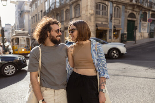 Couple in love looking each other while embracing and walking on old city street. High quality photo