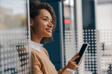 Stylish business woman is using phone standing in office during break time. High quality photo