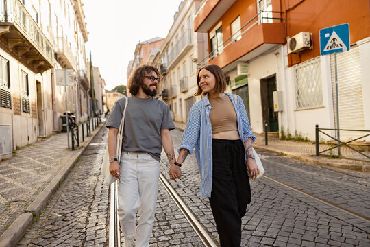 Smiling couple in love holding hands while walking on old city street. High quality photo