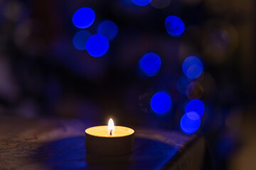 A burning candle against the background of a New Year tree. Blackout due to the war in Ukraine