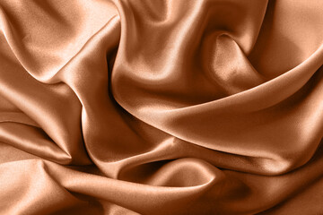 Texture of silk fabric toned with color of the year 2024 peach fuzz, close up