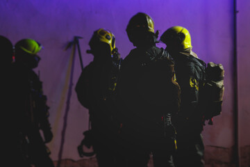 Group of fire men in protective uniform during fire fighting operation in the night city streets, firefighters brigade with the fire engine truck vehicle, emergency and rescue service