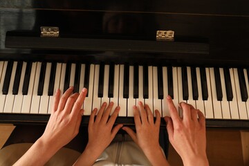 Young woman with child playing piano, above view. Music lesson