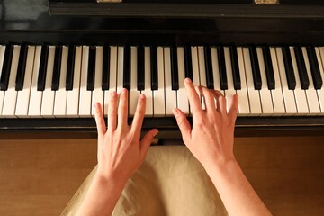 Young woman playing piano, above view. Music lesson