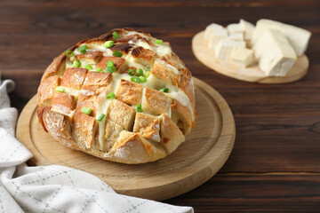 Freshly baked bread with tofu cheese and green onions on wooden table. Space for text