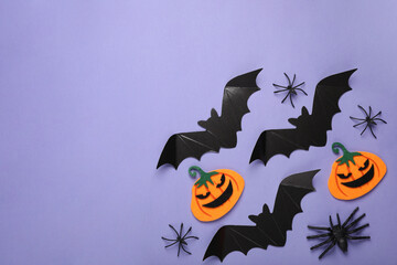Flat lay composition with cardboard bats, felt pumpkins and spiders on purple background, space for text. Halloween celebration
