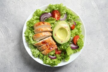 Delicious salad with chicken, avocado and vegetables on light grey table, top view