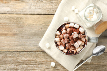Delicious hot chocolate with marshmallows and cocoa powder in cup on wooden table, flat lay. Space...
