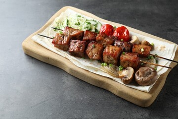 Delicious shish kebabs with vegetables and lavash on grey table