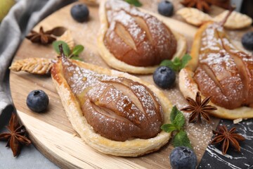 Delicious pears baked in puff pastry with powdered sugar served on table, closeup