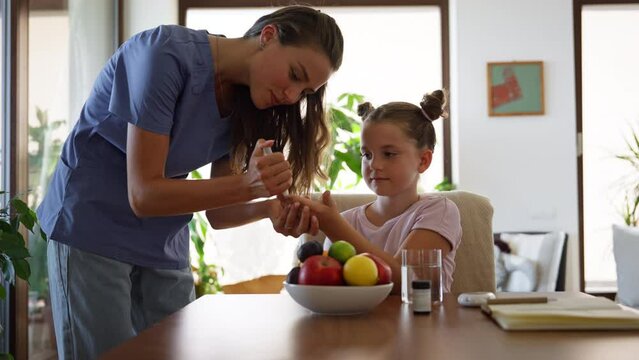Nurse checking girl's blood glucose level using a fingerstick glucose meter.