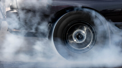Car burnout wheels tire with white smoke,Car wheel burnout with smoke from the spinning tyre, Drag car wheel burns tires preparation for the race.