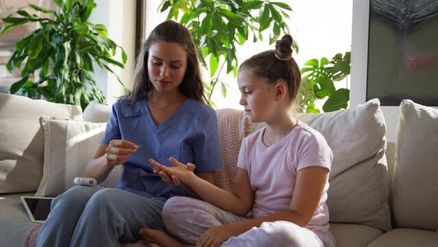 Nurse checking girl's blood glucose level using a fingerstick glucose meter.