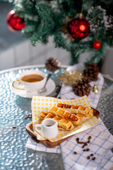Cup of hot coffee and bakery goods Various waffles and breads are on the table. and decorated with Christmas There is a Christmas tree and various decorations. to celebrate the Christmas festival.