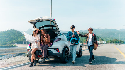 Group of Asian generation z people friends sitting on car trunk looking beautiful nature of countryside. Man and woman friendship enjoy and fun outdoor lifestyle road trip on summer holiday vacation. - obrazy, fototapety, plakaty
