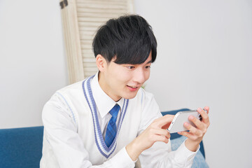 リビングスマートフォンで動画を見る男子高校生