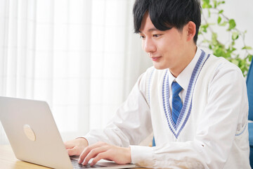 リビングでノートパソコンを使う男子高校生