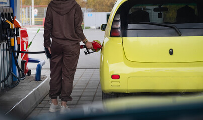 Attractive young woman refueling car at gas station. Female filling diesel at gasoline fuel in car...