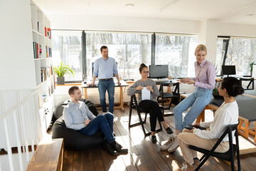 Happy diverse multiethnic colleagues coworkers sit in modern office talk brainstorm at casual...