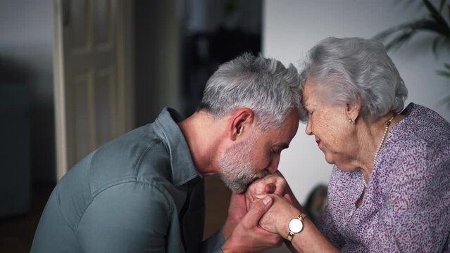 Portrait of mature man kissing his mothers hands.
