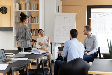 Diverse multiracial businesspeople brainstorm discuss company financial project on flip chart in...