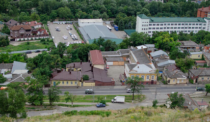 Fototapeta premium view of the city from the hill. top view of the roofs of houses and the road with cars.