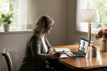 Remote learning for seniors. Focused aged female in modern headset study online on retirement...