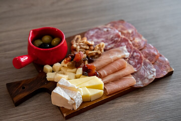 Cold cuts platter, variety of sliced meat and cheese with olives and nuts