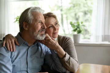 Dreams of mature love. Affectionate old age husband wife hug at cozy home look away dream recall good days of youth in memory. Caring senior spouses enjoy one another plan vacation together. Copyspace
