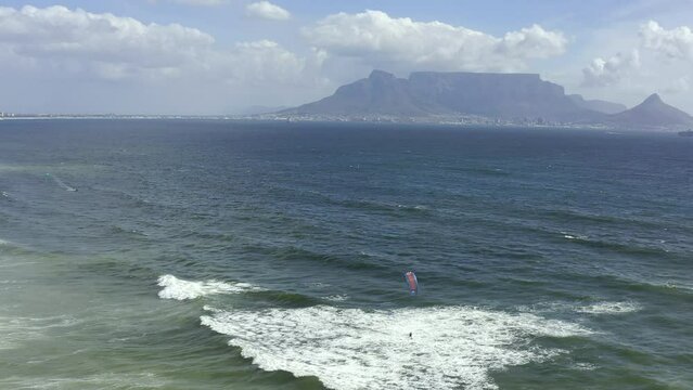 Drone of beach, sea and people kitesurfing in waves for outdoor adventure, travel and holiday or summer vacation. Aerial view of ocean water and surfer surfing in the wind in Cape Town South Africa