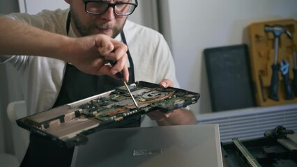 A man repairman makes repairs and repairs electronics in a home appliance repair shop