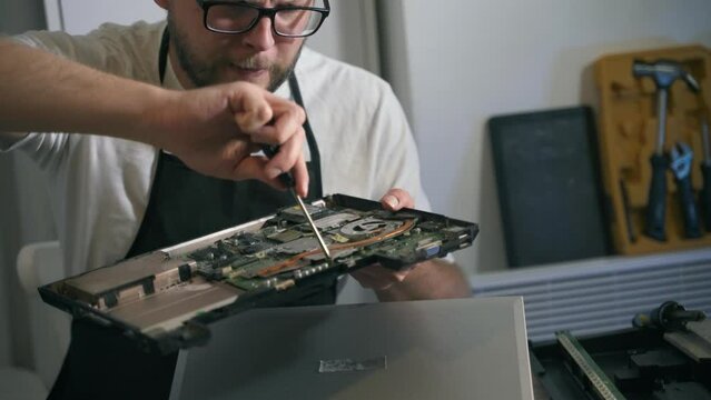 A man repairman makes repairs and repairs electronics in a home appliance repair shop