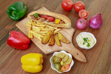 Arabic Shish Tawook Sandwich with bell pepper, onion, tomato, dip, hummus, veggies and fires isolated on wooden board side view arabic fastfood