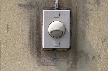 Doorbell ring on brown cements fence door of home.