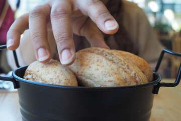 women hand pick baked bun on table 