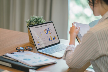 A female analyst analyzes KPI Business Analytics Data Dashboard Management System on a computer. - obrazy, fototapety, plakaty