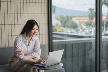 Smiling young asian businesswoman using laptop to work online, remote work.